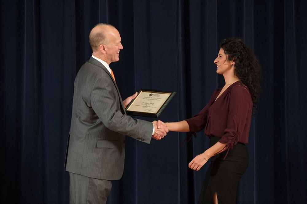 Doctor Potteiger shaking hands with an award recipient in a chocolate colored shirt
